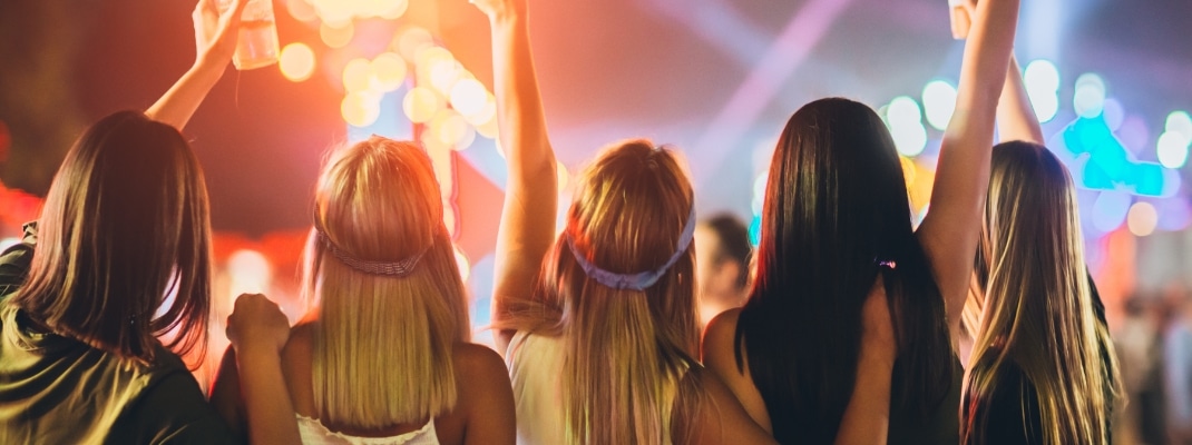 Back view of group of girls having fun at the music festival
