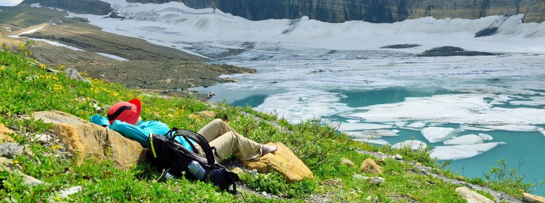 female hiker resting by the Grinnell glacier in Many Glaciers, Glacier National Park, Montana in summer
