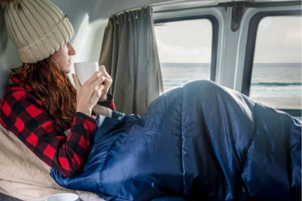 female in sleeping bag with coffee