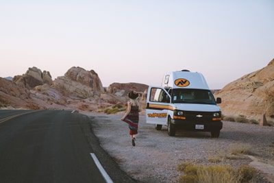 female running toward campervan in Valley of Fire