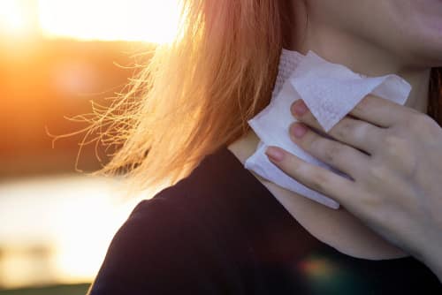 Woman wiping her neck with body wipe