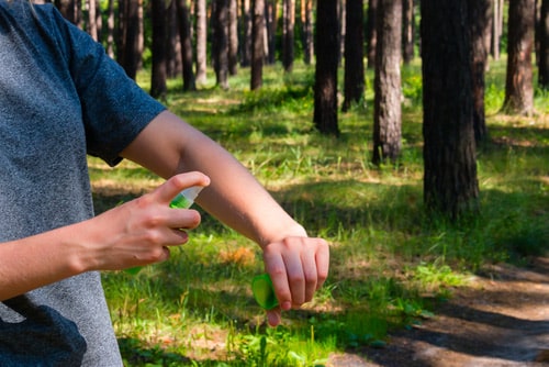 Person spraying insect repellent