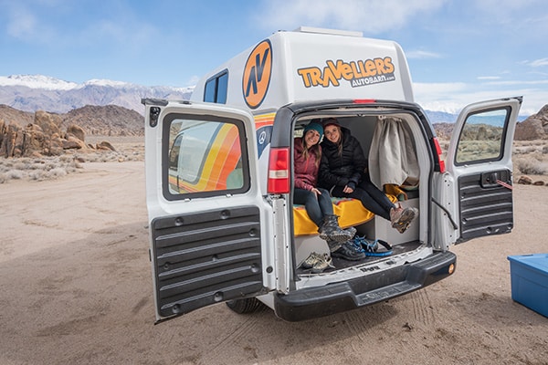 Two females sitting in the back of a campervan