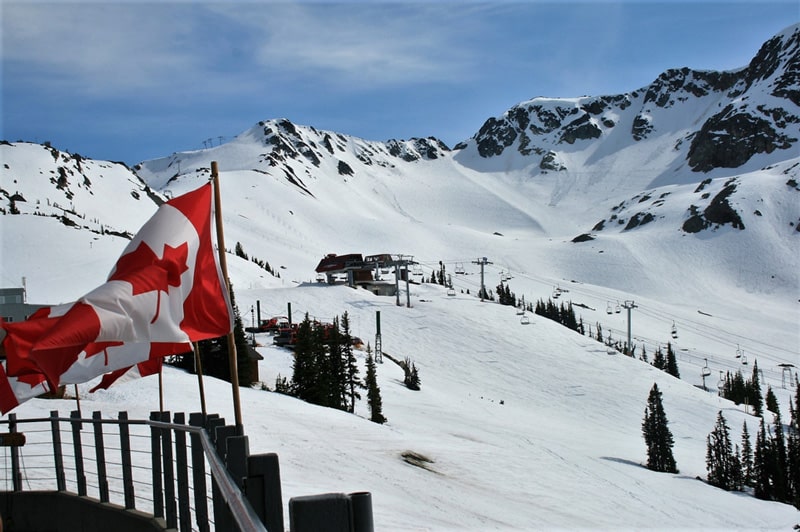 Snowy mountains and Canadian flag at Whistler Blackcomb, Canada