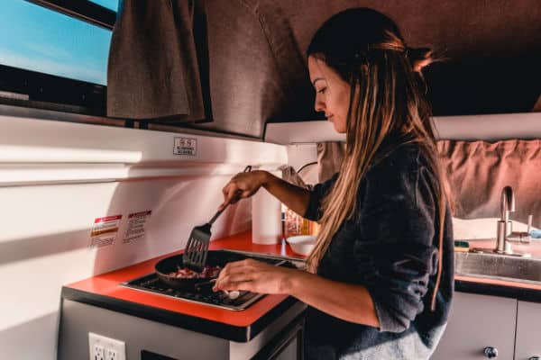 female cooking in campervan