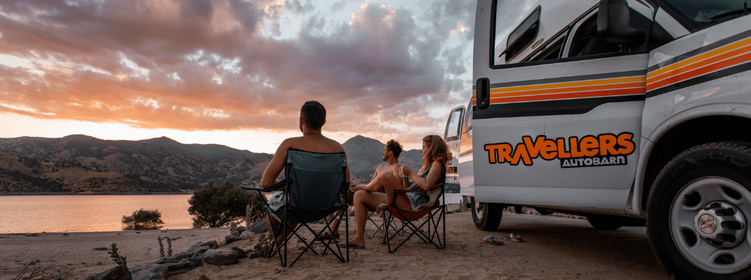 People sitting in camping chairs next to campervan 