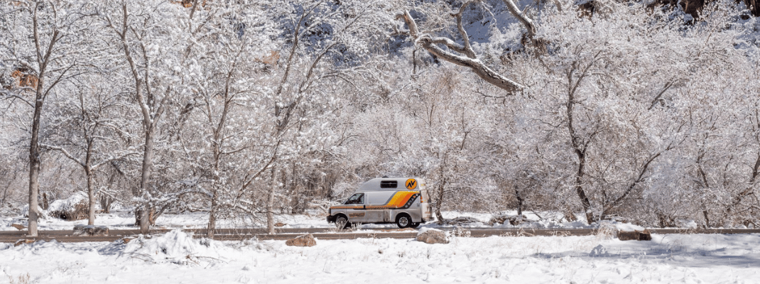 Campervan on road surrounded by snow