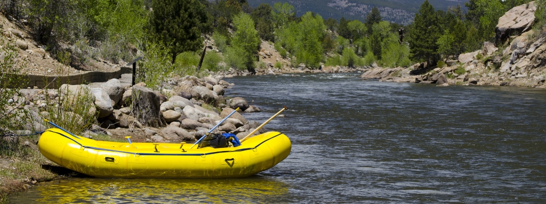 yellow river raft sits empty on the side of the Arkansas River in Buena Vista, Colorado