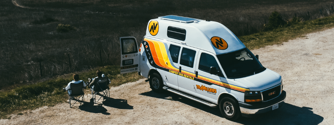 People sitting in camping chairs next to campervan, California