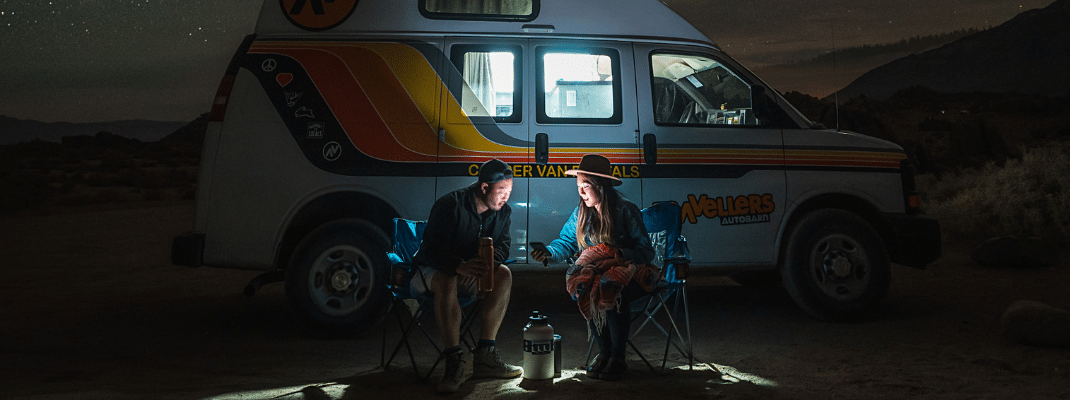 Sitting in camping chairs in front of campervan under the stars, USA