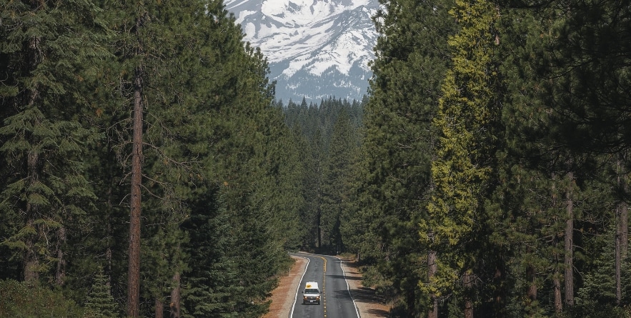 Campervan driving along road with background view of Mount Shasta, USA