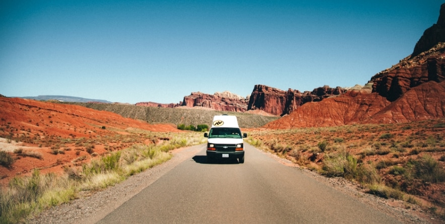 Campervan driving through red rock desert, USA