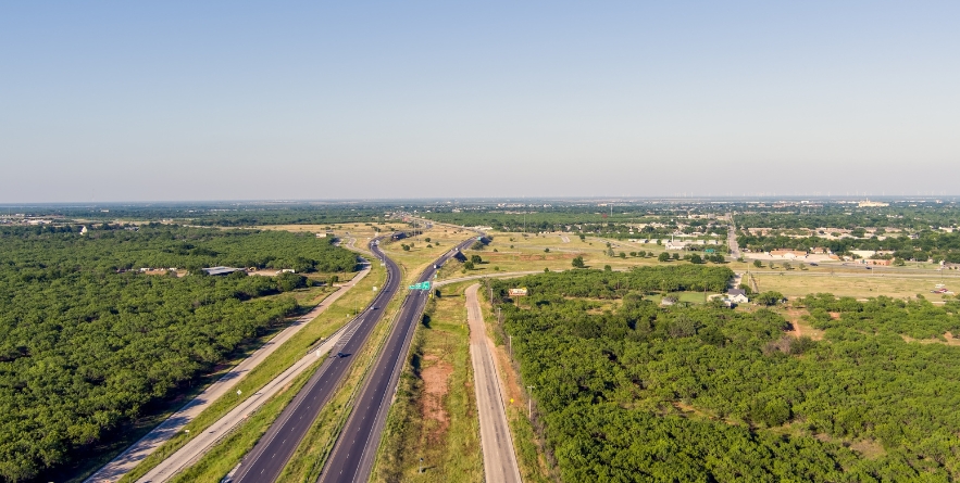 Aerial establishing shot of Abilene Texas with traffic flowing on highway 20 and a blue sky.