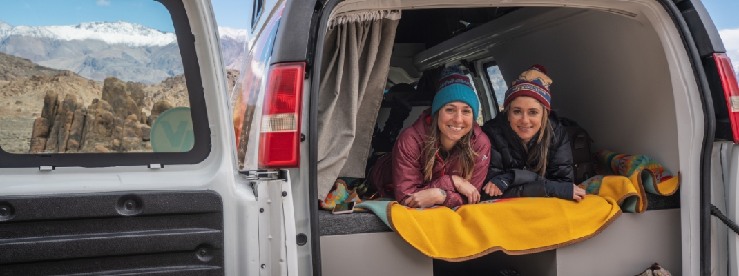 people sitting in back of campervan