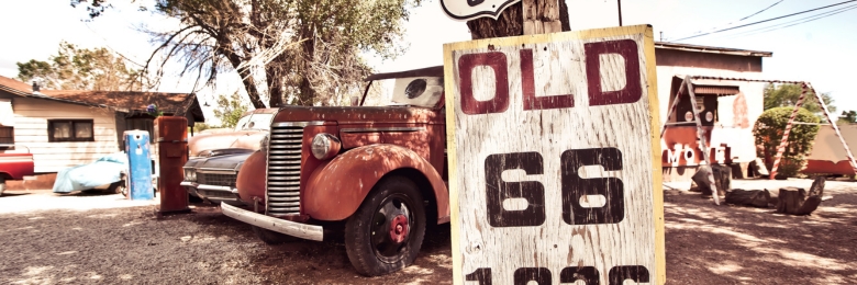 Old route 66 signs with rusty cars in background