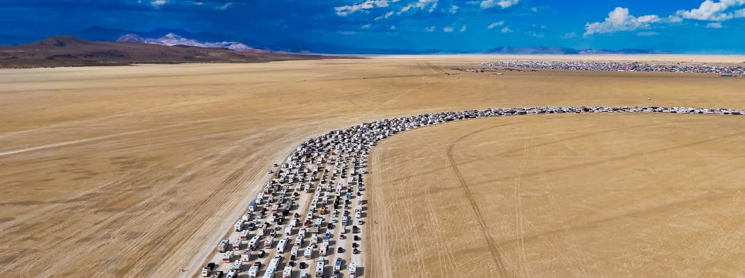 Burning Man traffic line on desert playa. Drone aerial view of thousands of cars lined up in the desert on their way to Burning Man festival.