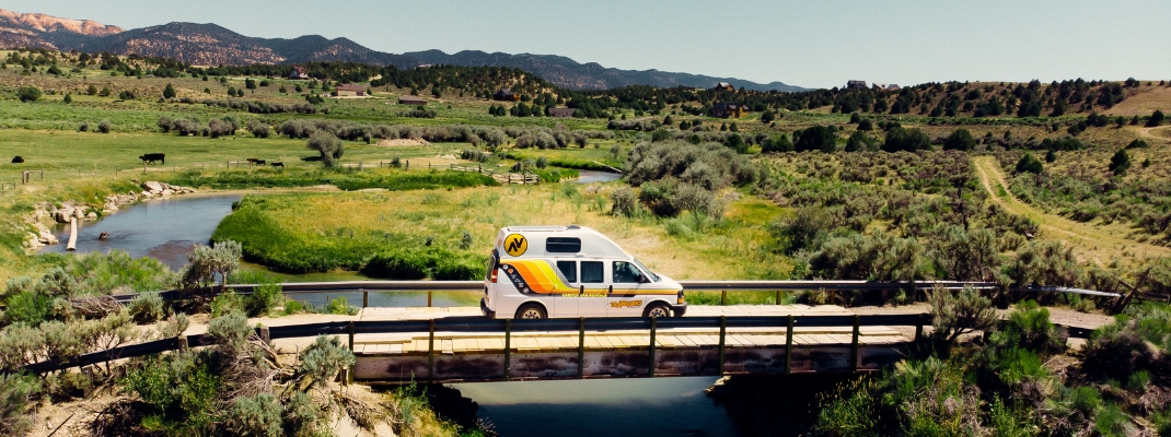 Campervan on bridge in grassy hill area