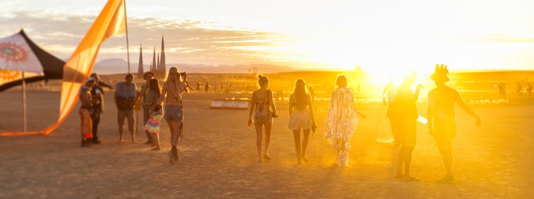 People walking towards sunset at a festival in the desert 