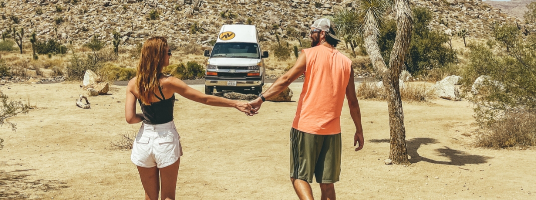 Two people walking towards campervan in desert