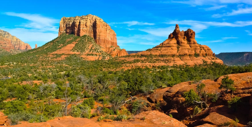 A view of Sedona's iconic Courthouse Butte and Bell Rock from a flat sandstone area called Yavapai Vista.