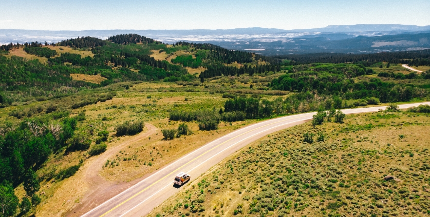 Drone image of a campervan on road in green landscape