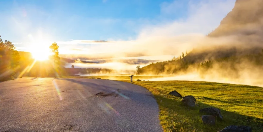 Morning sunlight and rising steam illuminate the Yellowstone River in Yellowstone National Park