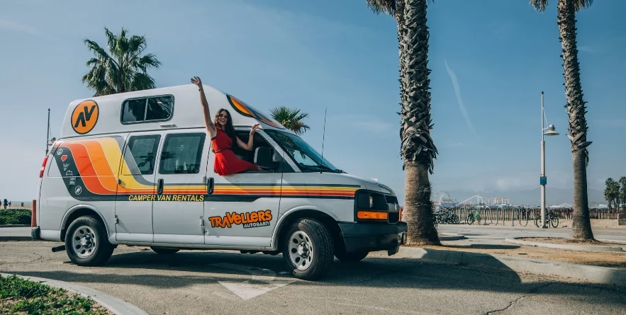 Person sitting in windowsill of campervan, Los Angeles beach